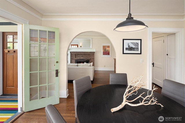 4529 Eastern Ave N, Seattle, WA 98103 - dining area featuring dark wood-type flooring, crown molding, a brick fireplace, arched walkways, and baseboards