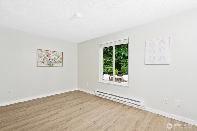 empty room featuring baseboard heating, wood finished floors, baseboards, and a textured ceiling