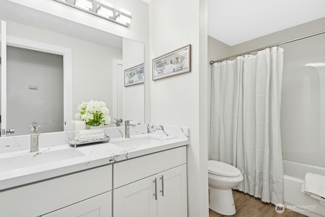 full bathroom featuring toilet, wood finished floors, double vanity, and shower / tub combo