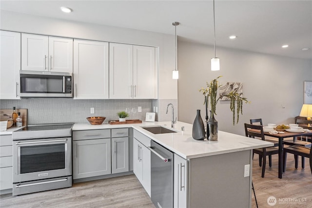825 238th Pl SE Unit D, Bothell, WA 98021 - kitchen featuring stainless steel appliances, a sink, a peninsula, light wood-type flooring, and decorative backsplash