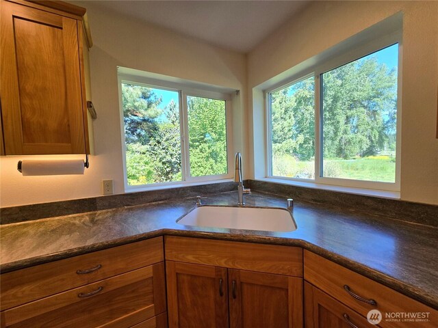 kitchen featuring a sink, brown cabinets, and dark stone countertops