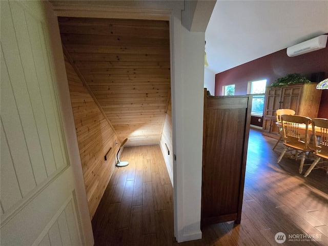 corridor with an AC wall unit, vaulted ceiling, hardwood / wood-style flooring, and wooden walls