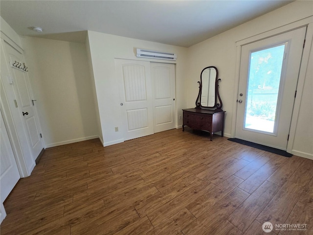 foyer featuring an AC wall unit, wood finished floors, and baseboards