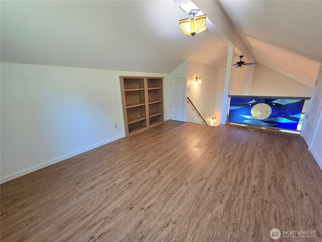 bonus room with wood finished floors, lofted ceiling, built in shelves, and baseboards