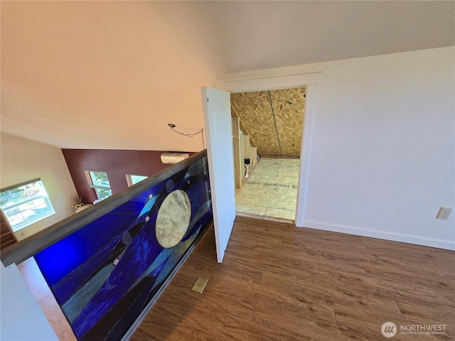 stairway featuring wood finished floors and lofted ceiling