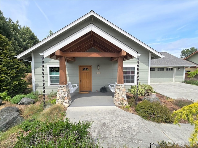 view of front of house featuring driveway, an attached garage, and a porch
