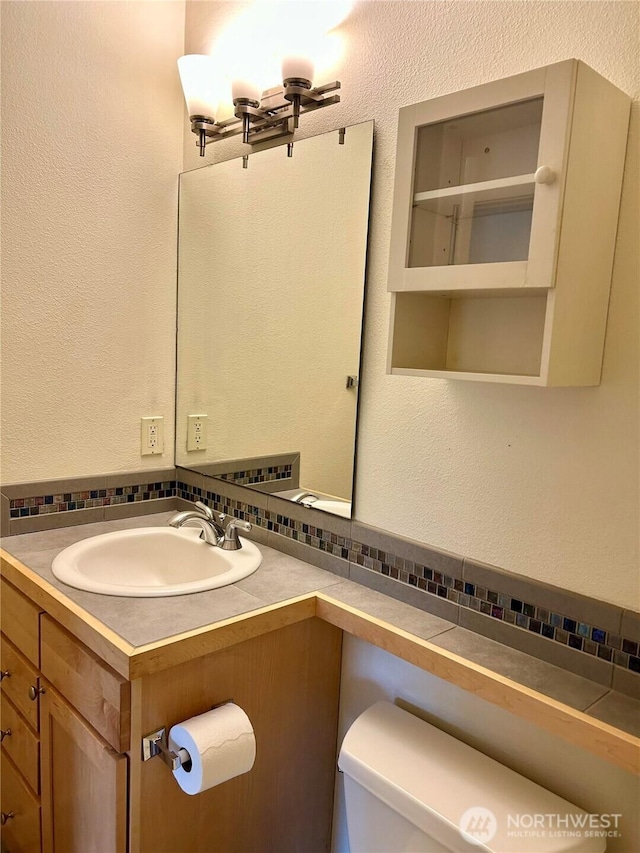 13426 97th Ave E Unit 301, Puyallup, WA 98373 - half bath with tasteful backsplash, vanity, toilet, and a textured wall