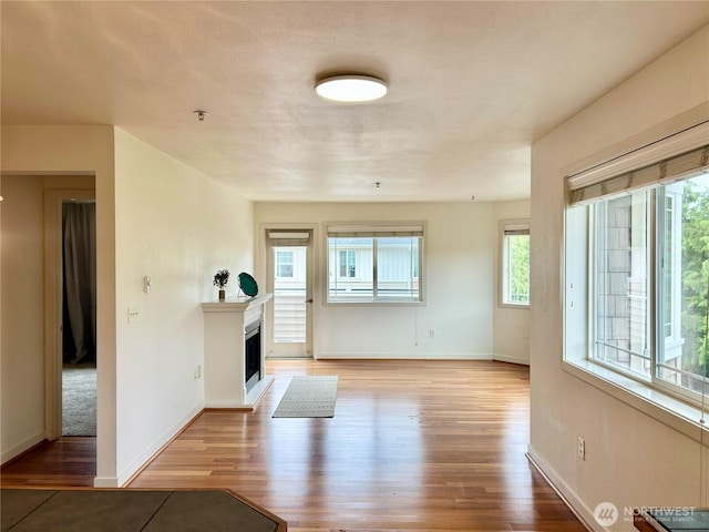 13426 97th Ave E Unit 301, Puyallup, WA 98373 - unfurnished living room with wood finished floors, a fireplace, and baseboards