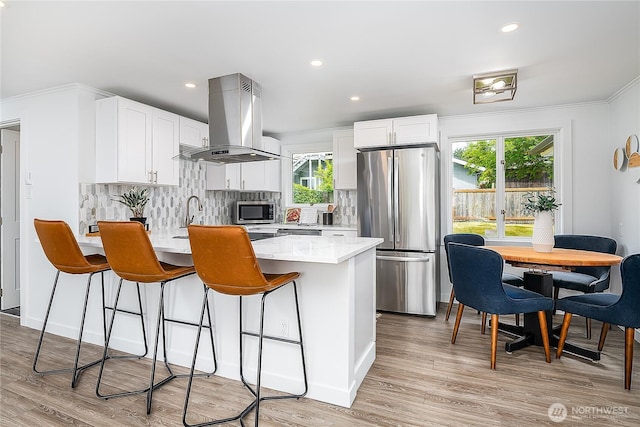5705 241st St SW, Mountlake Terrace, WA 98043 - kitchen with appliances with stainless steel finishes, island range hood, a peninsula, decorative backsplash, and plenty of natural light
