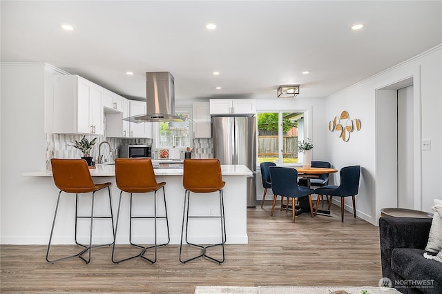 5705 241st St SW, Mountlake Terrace, WA 98043 - kitchen with island exhaust hood, a peninsula, light countertops, decorative backsplash, and white cabinetry
