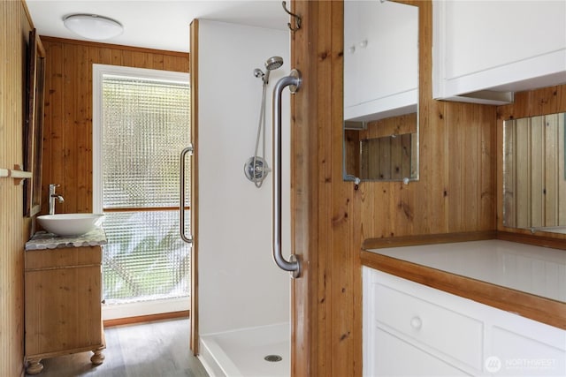3115 Saratoga Rd, Langley, WA 98260 - bathroom featuring vanity, wood walls, a shower stall, healthy amount of natural light, and wood finished floors