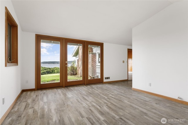 3115 Saratoga Rd, Langley, WA 98260 - empty room featuring wood finished floors, lofted ceiling, a water view, baseboards, and french doors