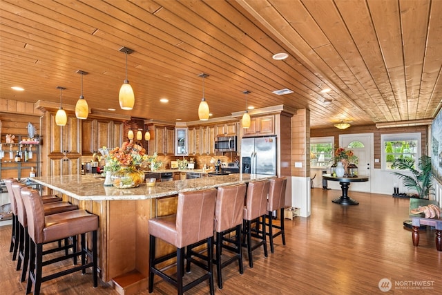 8116 Naketa Beach Walk, Mukilteo, WA 98275 - kitchen with stainless steel appliances, wooden ceiling, dark wood-type flooring, brown cabinetry, and light stone countertops