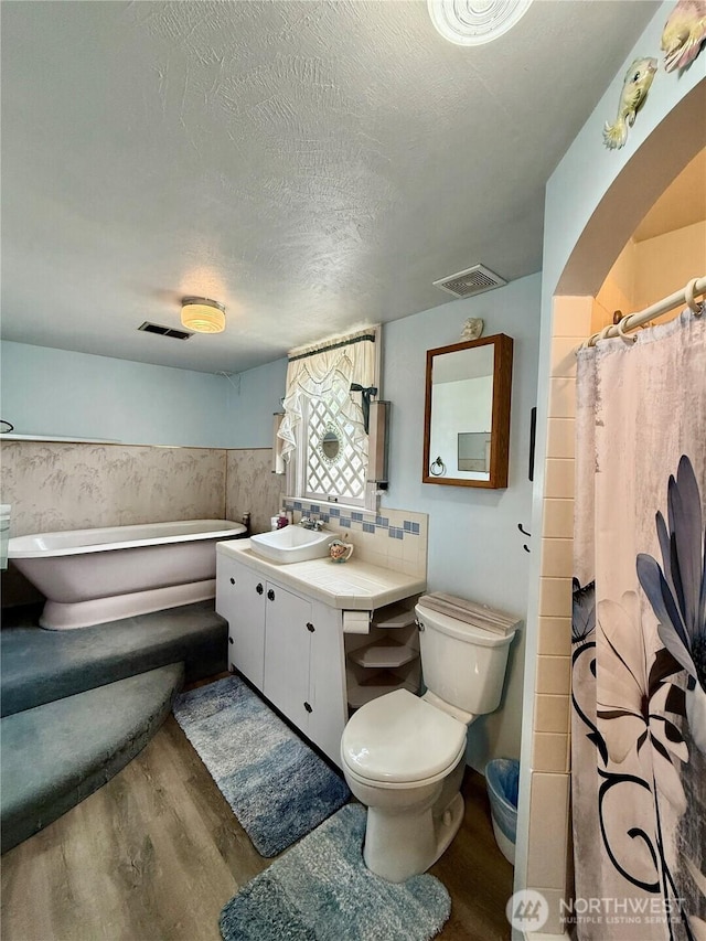 303307 N 3rd St, Dayton, WA 99328 - full bath featuring wood finished floors, vanity, toilet, a bath, and wainscoting