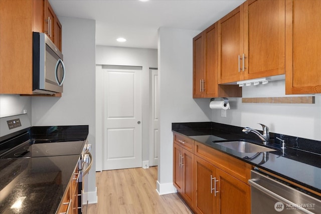 21307 48th Ave W Unit C206, Mountlake Terrace, WA 98043 - kitchen with appliances with stainless steel finishes, a sink, brown cabinetry, light wood-style floors, and dark stone counters
