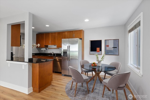 21307 48th Ave W Unit C206, Mountlake Terrace, WA 98043 - kitchen featuring appliances with stainless steel finishes, dark countertops, brown cabinets, light wood finished floors, and baseboards