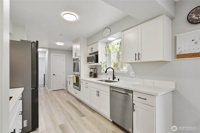 16015 Lange Rd, Mount Vernon, WA 98273 - kitchen with appliances with stainless steel finishes, a sink, white cabinets, and light wood-style flooring