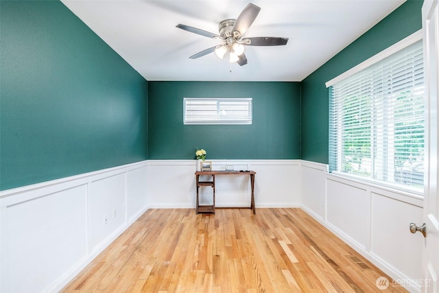 7628 Kodiak Ave NE, Lacey, WA 98516 - spare room with light wood-style floors, plenty of natural light, a ceiling fan, wainscoting, and a decorative wall