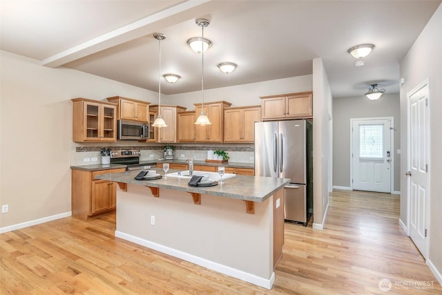 7628 Kodiak Ave NE, Lacey, WA 98516 - kitchen featuring appliances with stainless steel finishes, tasteful backsplash, a kitchen breakfast bar, a kitchen island with sink, and light wood-style flooring