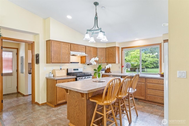 25420 354th Ave SE, Ravensdale, WA 98051 - kitchen with stainless steel range with gas cooktop, under cabinet range hood, a sink, light countertops, and a breakfast bar
