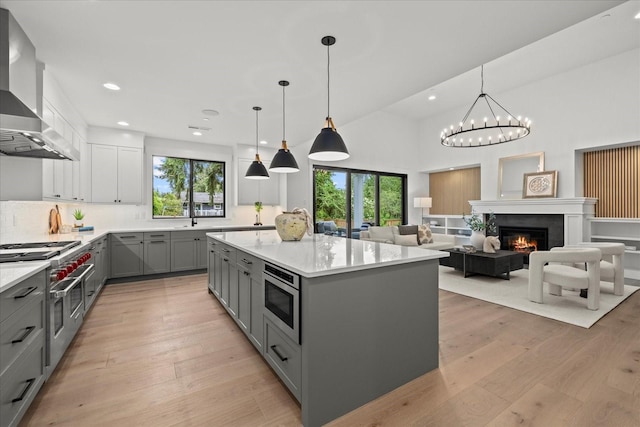 11440 109th Ave NE, Kirkland, WA 98033 - kitchen featuring gray cabinets, wall chimney range hood, stainless steel appliances, a kitchen island, and backsplash