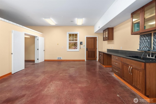 26970 SE Old Black Nugget Rd, Issaquah, WA 98029 - kitchen featuring a sink, concrete floors, baseboards, glass insert cabinets, and dark countertops