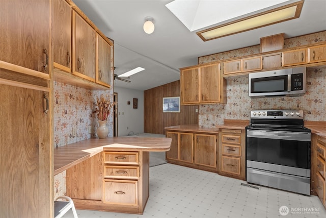 11436SE 208th St Unit 180, Kent, WA 98031 - kitchen featuring appliances with stainless steel finishes, a skylight, a peninsula, light countertops, and vaulted ceiling