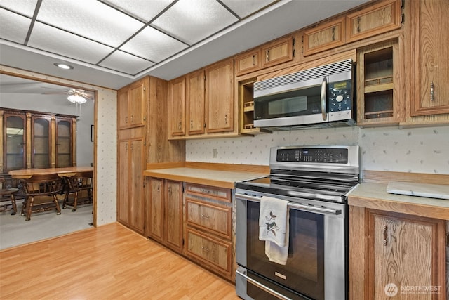 11436SE 208th St Unit 188, Kent, WA 98031 - kitchen featuring appliances with stainless steel finishes, light countertops, brown cabinetry, light wood finished floors, and wallpapered walls