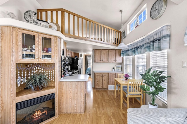 7704 Birch Bay Dr Unit 2805, Blaine, WA 98230 - kitchen featuring light wood-style floors, a high ceiling, brown cabinets, light countertops, and glass insert cabinets
