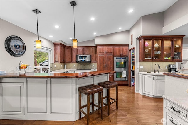 6753 Forest Ridge Dr, Wenatchee, WA 98801 - kitchen with appliances with stainless steel finishes, vaulted ceiling, backsplash, glass insert cabinets, and hanging light fixtures