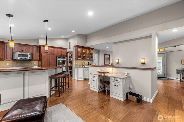 6753 Forest Ridge Dr, Wenatchee, WA 98801 - kitchen with appliances with stainless steel finishes, a kitchen breakfast bar, glass insert cabinets, light wood-style flooring, and recessed lighting