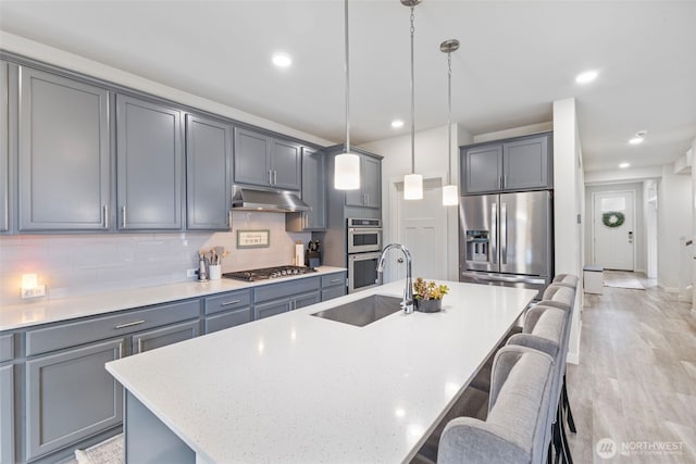 18230 134th Ave E, Puyallup, WA 98374 - kitchen featuring a sink, stainless steel appliances, under cabinet range hood, a kitchen breakfast bar, and gray cabinets
