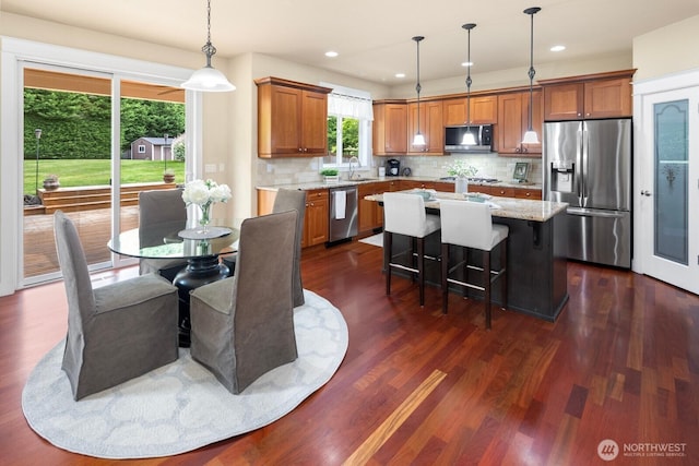 21515 26th St E, Lake Tapps, WA 98391 - kitchen with appliances with stainless steel finishes, a sink, brown cabinetry, dark wood-style floors, and tasteful backsplash