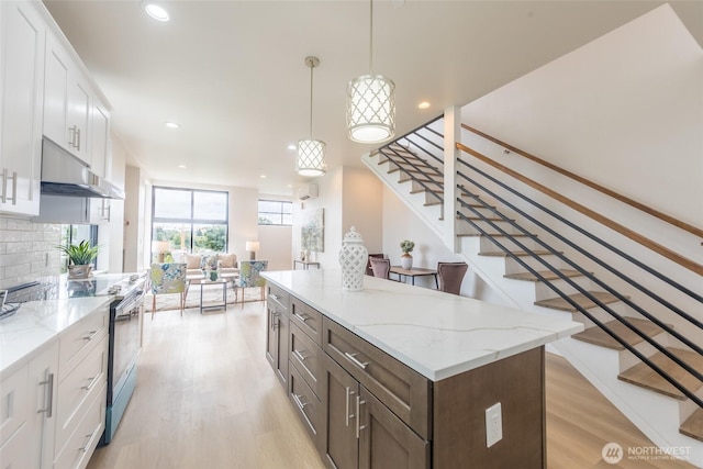 1019 Sturgus Ave S Unit A, Seattle, WA 98144 - kitchen with electric range, under cabinet range hood, light wood-style floors, white cabinetry, and recessed lighting