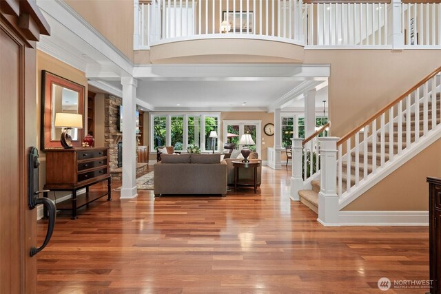 2920 39th Ln NW, Olympia, WA 98502 - living room with decorative columns, wood finished floors, stairs, a towering ceiling, and baseboards
