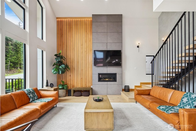 400 Hyak Dr E, Snoqualmie Pass, WA 98068 - living room featuring a high ceiling, a tiled fireplace, stairs, and wood finished floors