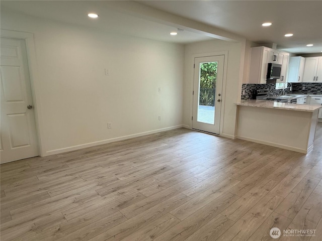 kitchen with stainless steel appliances, light wood finished floors, tasteful backsplash, white cabinetry, and a sink