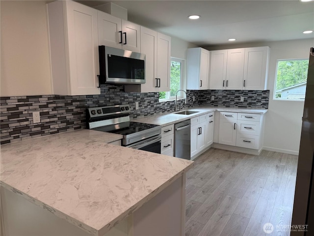 kitchen featuring appliances with stainless steel finishes, a sink, healthy amount of natural light, light wood-style flooring, and recessed lighting