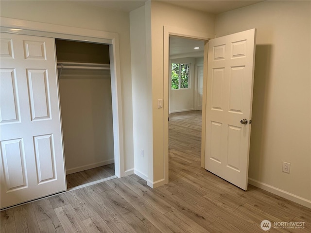 unfurnished bedroom with light wood finished floors, baseboards, and a closet