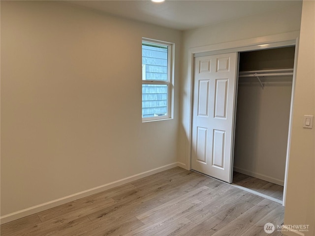unfurnished bedroom with light wood-style floors, baseboards, and a closet
