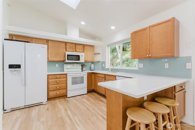 4 Alder Ct, Bellingham, WA 98229 - kitchen featuring white appliances, a peninsula, light wood-style flooring, vaulted ceiling, and decorative backsplash