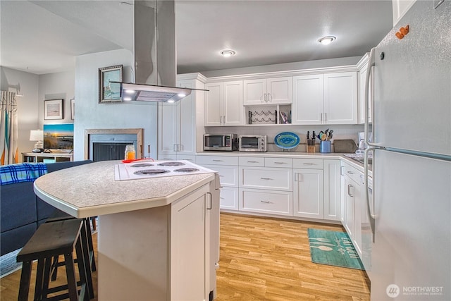 7806 Birch Bay Dr Unit 1007, Blaine, WA 98230 - kitchen featuring freestanding refrigerator, island range hood, stainless steel microwave, cooktop, and light wood finished floors