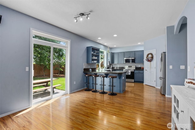 176 Raspberry Ln, Woodland, WA 98674 - kitchen featuring stainless steel appliances, a peninsula, a breakfast bar area, backsplash, and light wood-style flooring