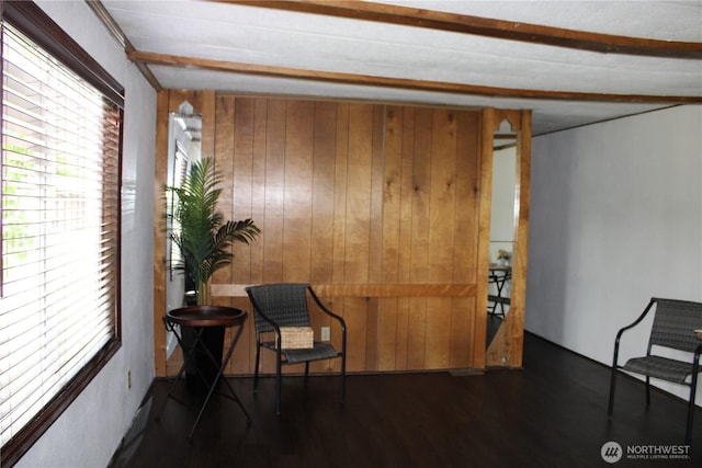 sitting room with wood walls, wood finished floors, and beamed ceiling