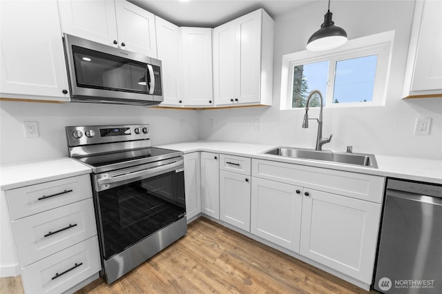 7409 Myers Rd, Bonney Lake, WA 98391 - kitchen with appliances with stainless steel finishes, light countertops, white cabinetry, light wood-style floors, and decorative light fixtures