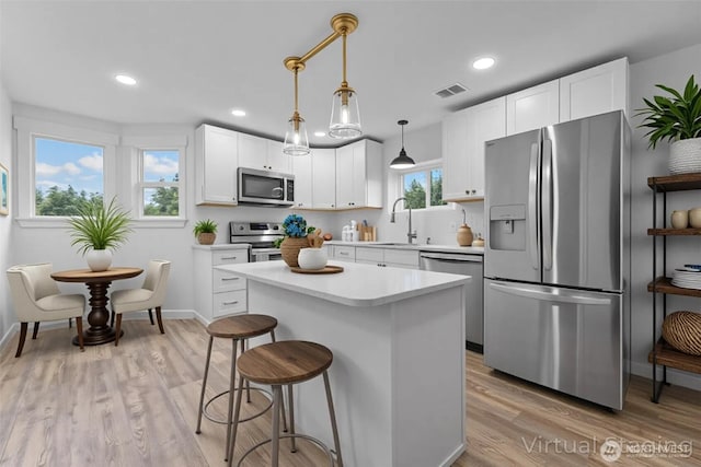 7409 Myers Rd, Bonney Lake, WA 98391 - kitchen with appliances with stainless steel finishes, light countertops, light wood-type flooring, a breakfast bar, and a center island