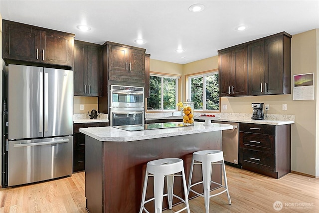 13218 42nd Ave W, Mukilteo, WA 98275 - kitchen featuring appliances with stainless steel finishes, a breakfast bar area, light wood-type flooring, dark brown cabinetry, and recessed lighting