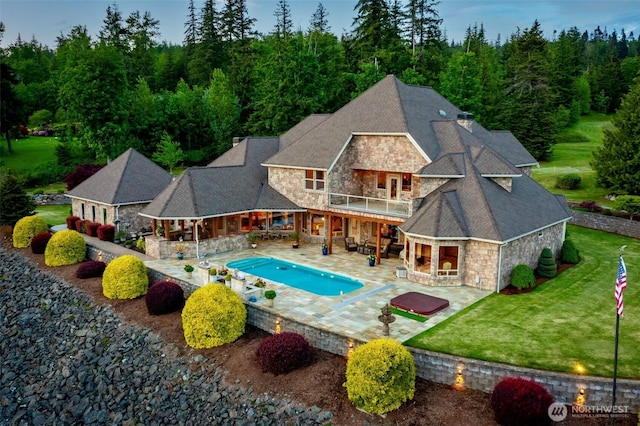1844 Vineyard Pl, Bellingham, WA 98226 - rear view of house featuring stone siding, a balcony, a lawn, a patio, and an outdoor pool