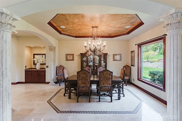 1844 Vineyard Pl, Bellingham, WA 98226 - dining space featuring decorative columns, a raised ceiling, arched walkways, a chandelier, and baseboards