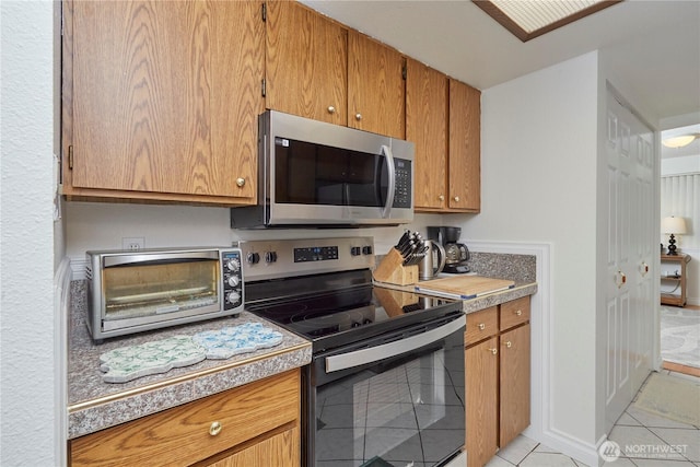 3135 Rustlewood Ln SE, Port Orchard, WA 98366 - kitchen with stainless steel appliances, light tile patterned floors, light countertops, and brown cabinets